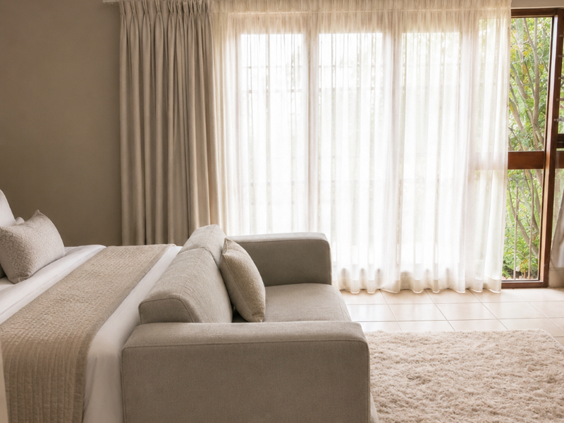 A well-lit bedroom featuring neutral tiled flooring and a large sliding glass door that provides direct access to the outdoor area.