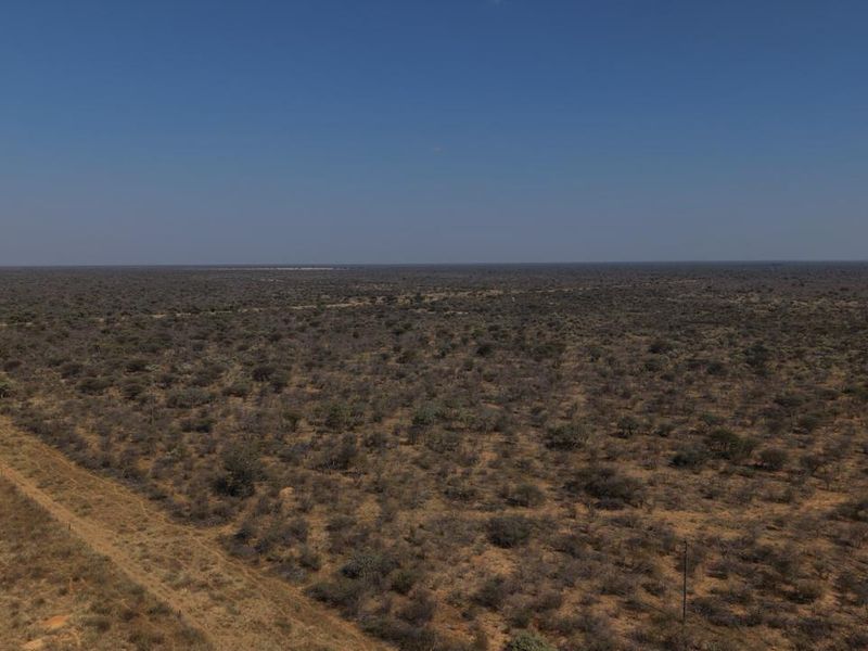 An aerial view of the expansive farm landscape, featuring natural bushveld vegetation and a dirt access track.