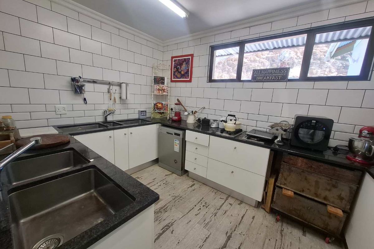 Functional kitchen featuring white cabinetry, granite countertops, subway tile backsplash, and double stainless steel sinks with ample workspace.