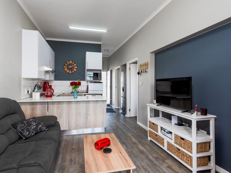 An open-plan living and kitchen area featuring modern cabinetry, laminate countertops, and durable flooring, creating a functional and cohesive living space.