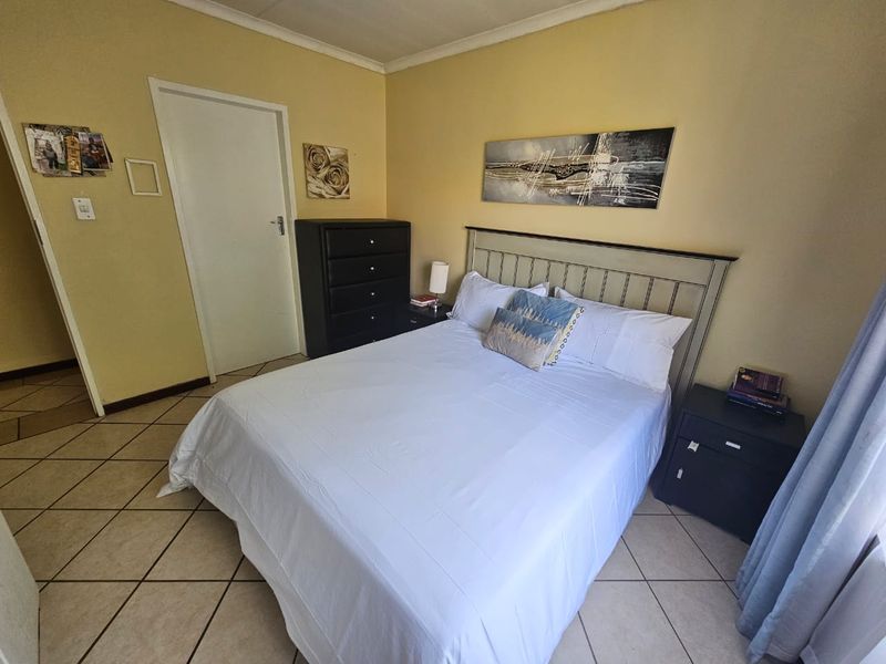 A functional bedroom featuring tiled flooring and neutral wall finishes, providing a comfortable and well-maintained living space.