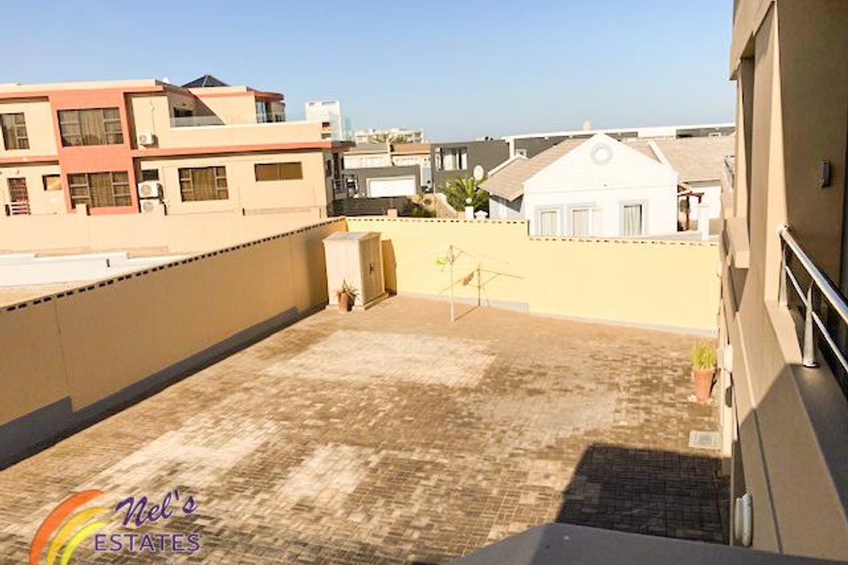 An elevated view of a paved rear courtyard area featuring high boundary walls, providing a private outdoor space.