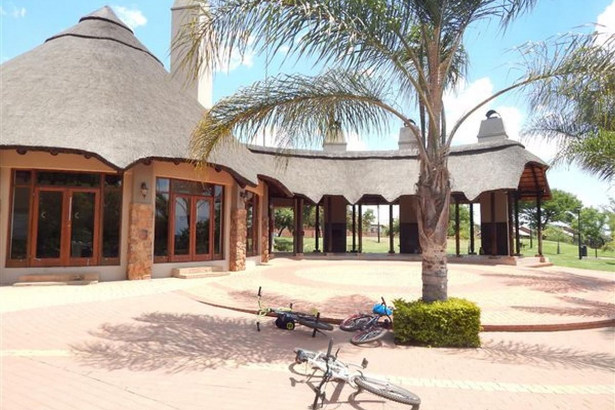 Spacious rear patio area featuring a distinctive thatched roof design, stone-clad accents, and large timber-framed glass doors leading into the main living space.