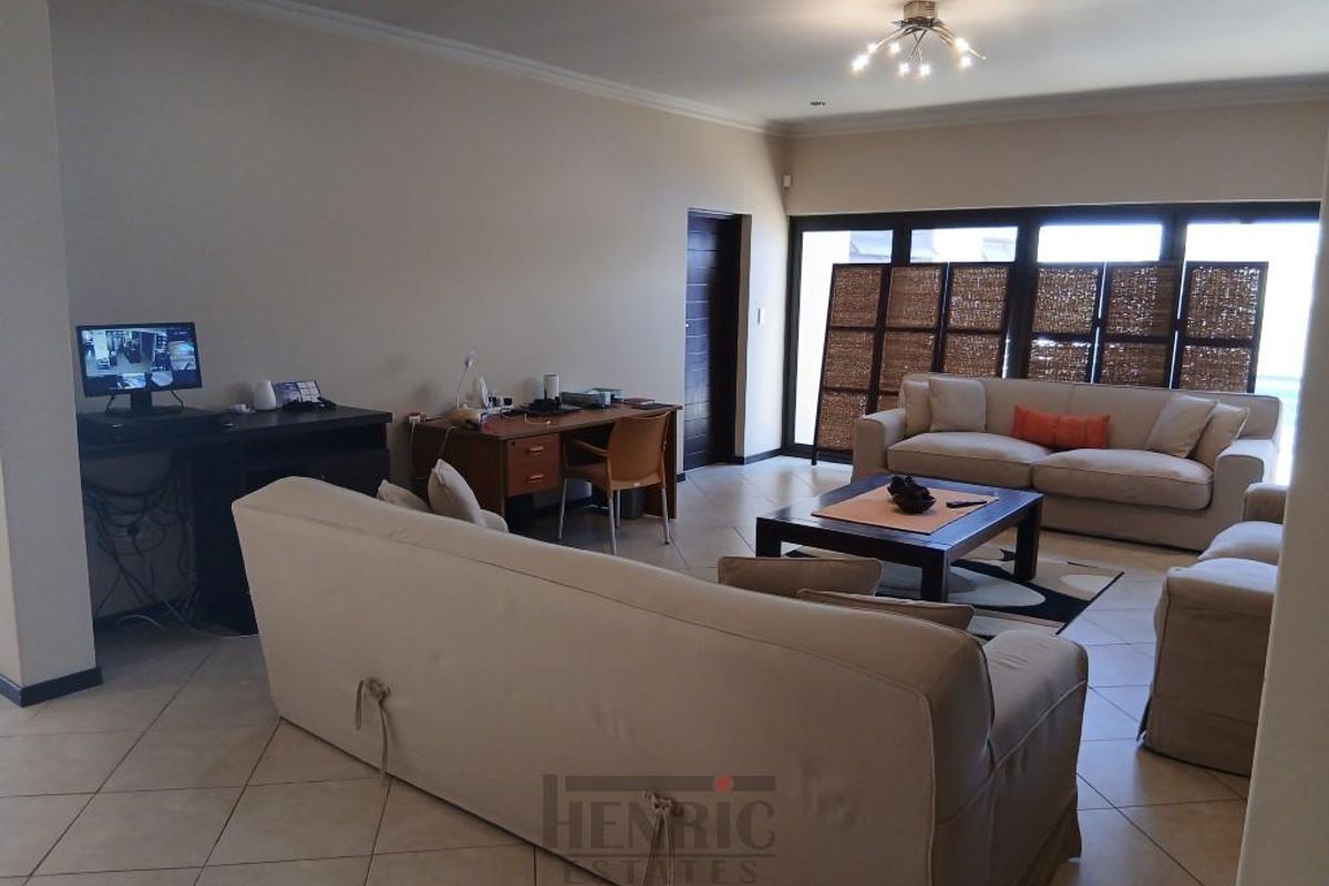 Spacious open-plan living area featuring tiled flooring, recessed ceiling lighting, and large sliding glass doors providing access to the outdoor space.