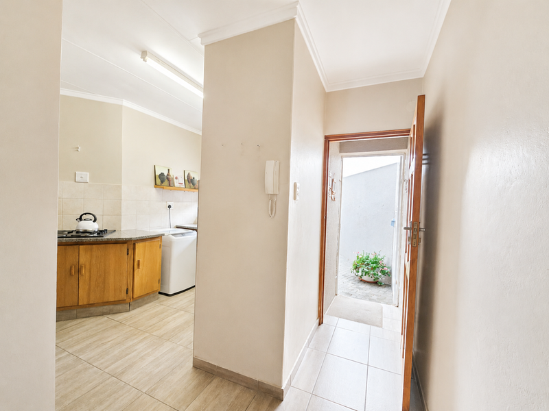 A functional kitchen featuring timber cabinetry, granite countertops, and a gas hob, with direct access to an outdoor courtyard area.