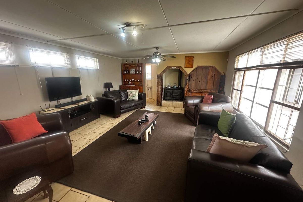 Spacious living room featuring tiled flooring, a built-in wood-burning stove, and large windows providing ample natural light.