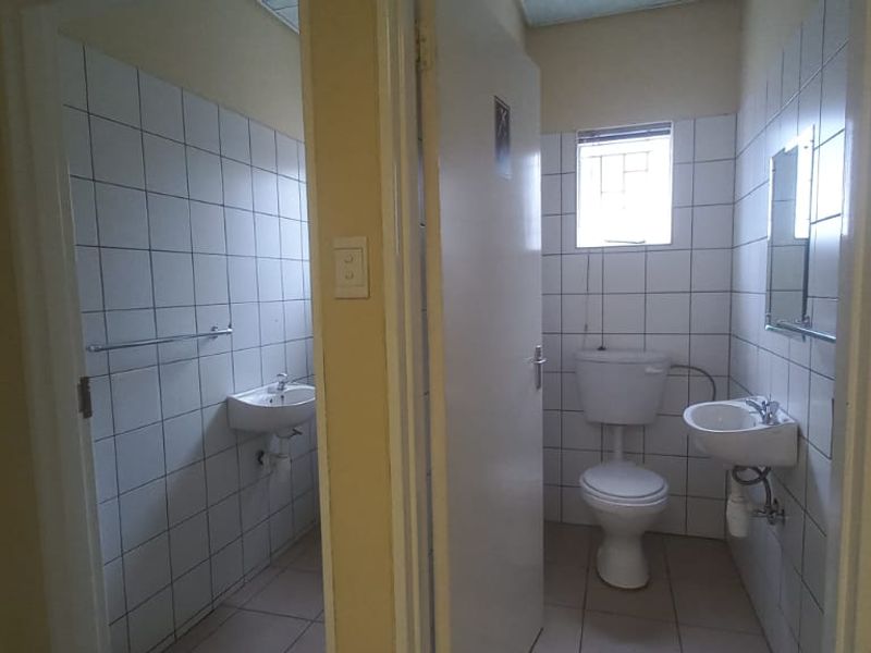 Functional industrial bathroom facility featuring dual washbasins, tiled walls, and standard sanitary ware in a clean, utilitarian layout.