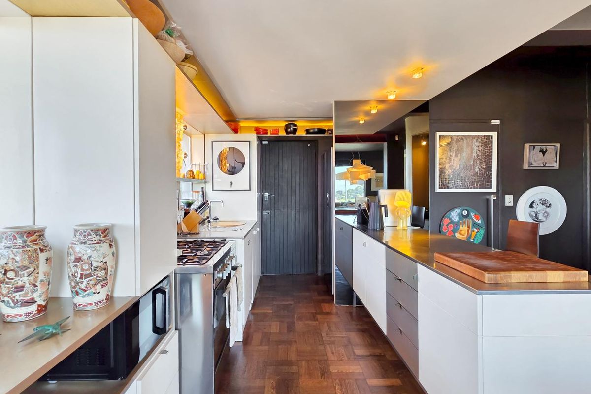 Modern kitchen featuring high-end cabinetry, stainless steel countertops, a gas stove, built-in microwave, and rich parquet flooring with integrated lighting.