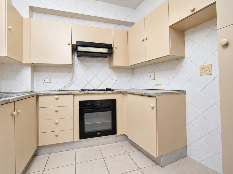 A dated kitchen featuring built-in cabinetry, laminate countertops, an integrated oven, and a tiled backsplash, offering a functional layout ready for modernization.