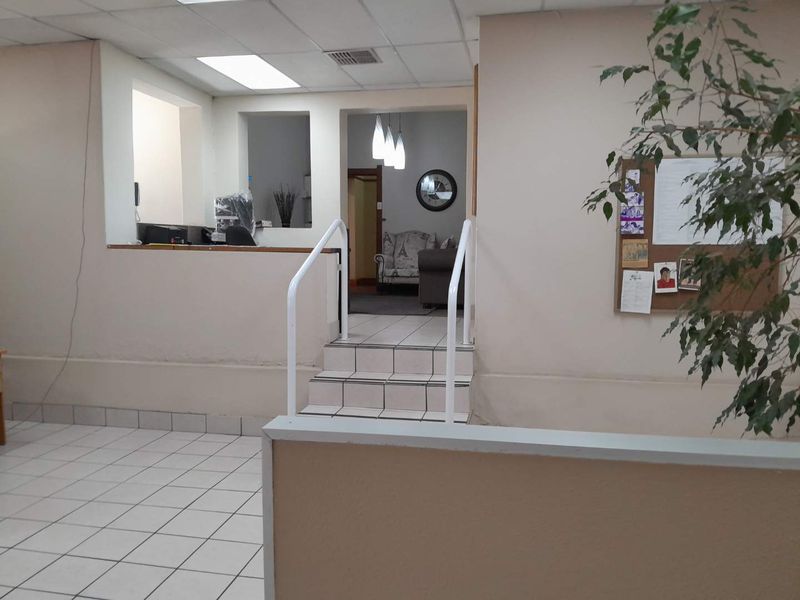 An entry area featuring tiled flooring, a reception counter, and a small staircase leading to an adjacent room.