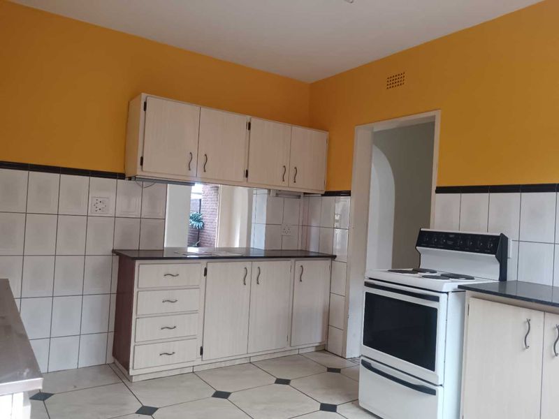 A functional kitchen featuring built-in cabinetry, tiled backsplash, and a freestanding stove, offering a practical layout with potential for modern cosmetic updates.