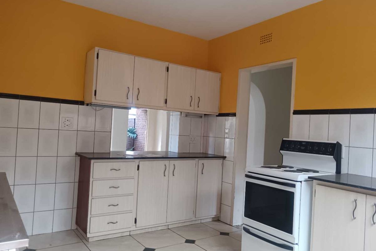 A functional kitchen featuring built-in cabinetry, tiled backsplash, and a freestanding stove, offering a practical layout with potential for modern cosmetic updates.