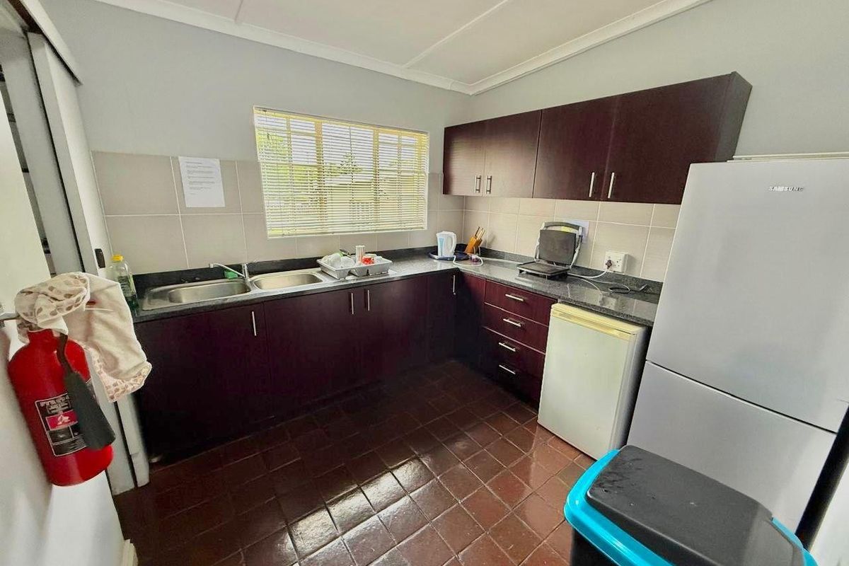 A functional kitchen featuring dark wood-finish cabinetry, granite-look countertops, a double stainless steel sink, and tiled flooring.