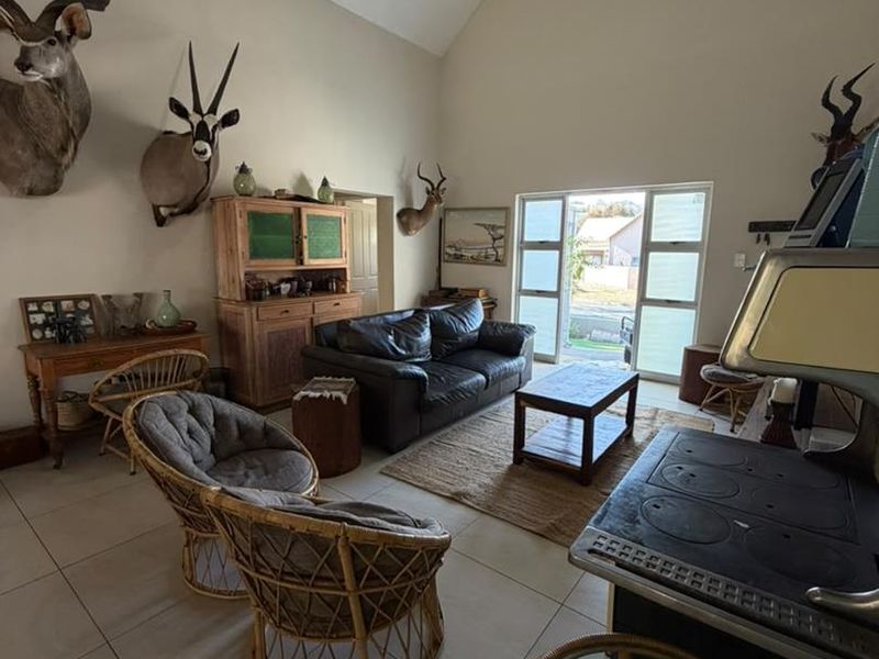 Spacious open-plan living area featuring a vaulted ceiling, tiled floors, and a traditional cast iron stove, with direct access to the outdoors.