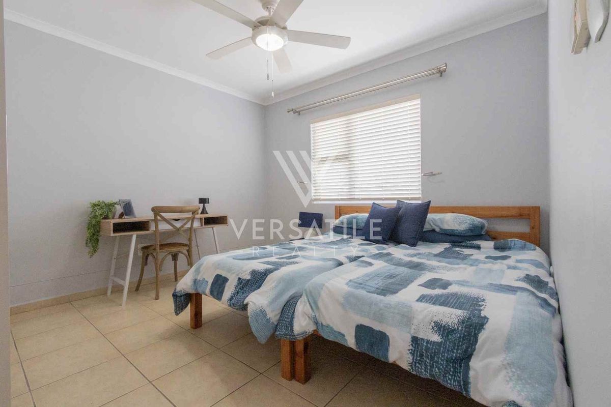 A bedroom featuring tiled flooring, a ceiling fan, and a window with fitted blinds.
