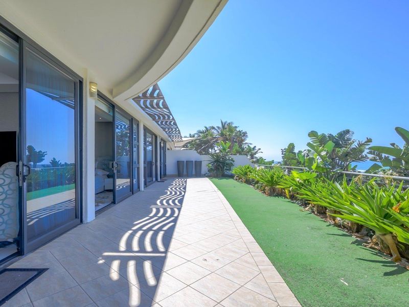 Spacious balcony featuring tiled flooring, a decorative pergola, and a metal balustrade, offering seamless indoor-outdoor flow through large sliding glass doors.