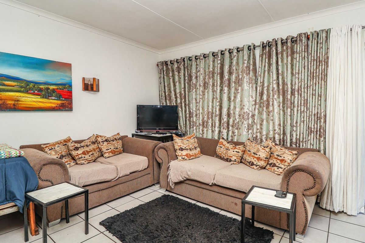 A living room featuring tiled flooring and a sliding glass door providing access to an outdoor patio area.