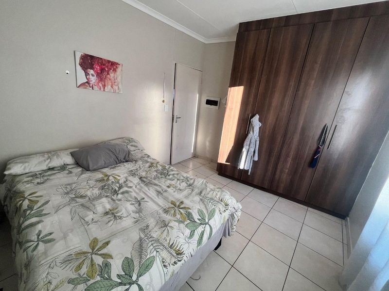 A bedroom featuring tiled flooring and dark wood built-in cupboards, providing functional storage space.