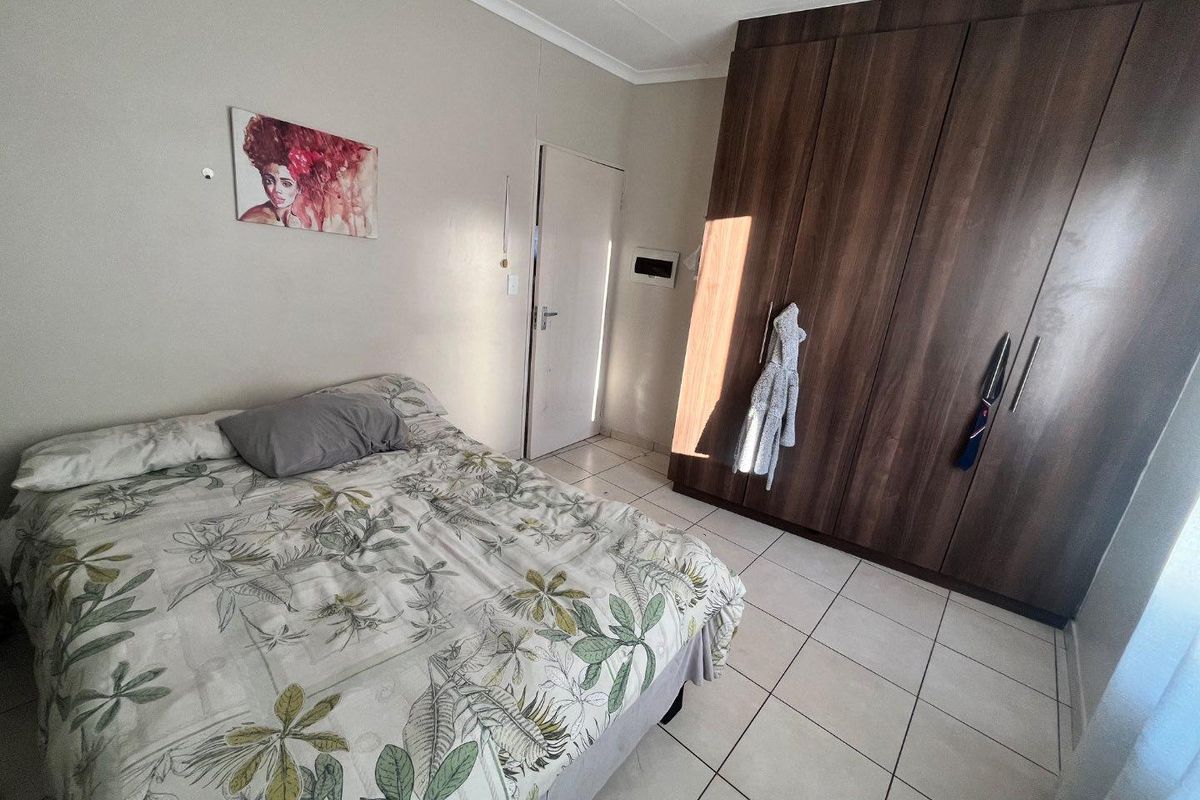 A bedroom featuring tiled flooring and dark wood built-in cupboards, providing functional storage space.