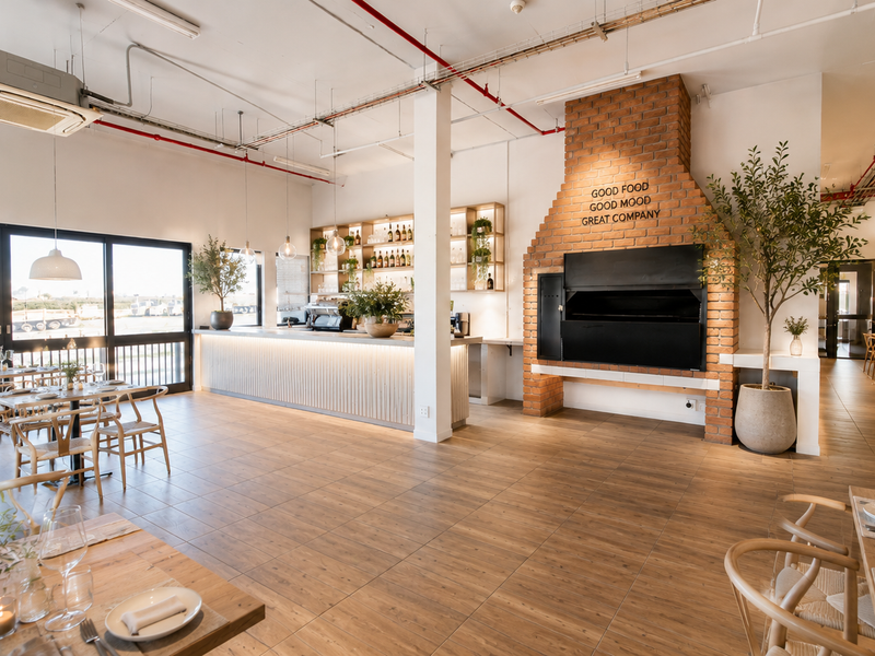 Spacious open-plan industrial-style dining area featuring a prominent brick fireplace, built-in bar counter, and large sliding glass doors providing ample natural light.