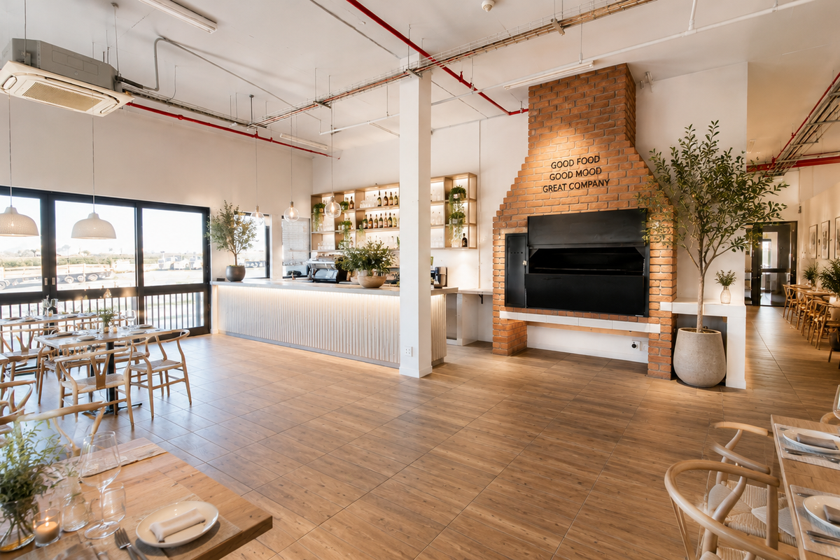 Spacious open-plan industrial-style dining area featuring a prominent brick fireplace, built-in bar counter, and large sliding glass doors providing ample natural light.