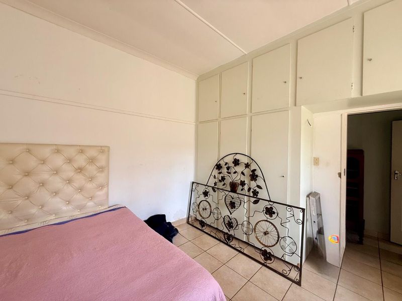 Bedroom featuring tiled flooring and extensive built-in cupboard storage, requiring minor cosmetic updates to the wall finishes.