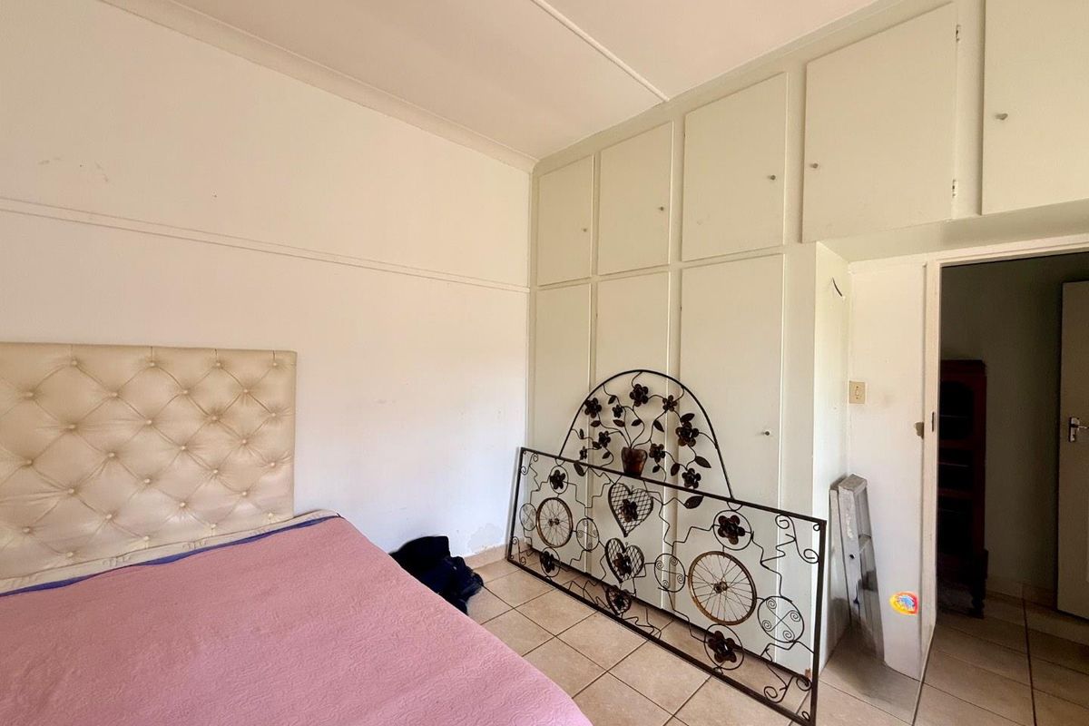 Bedroom featuring tiled flooring and extensive built-in cupboard storage, requiring minor cosmetic updates to the wall finishes.