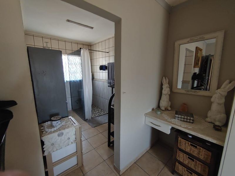 A functional bathroom featuring a walk-in shower with tiled walls and flooring, adjacent to a small dressing or vanity area.