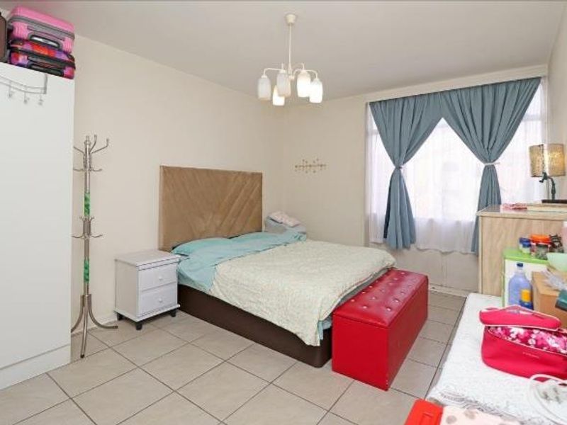 A functional bedroom featuring tiled flooring and a central ceiling light fixture, offering a neutral base for personalization.