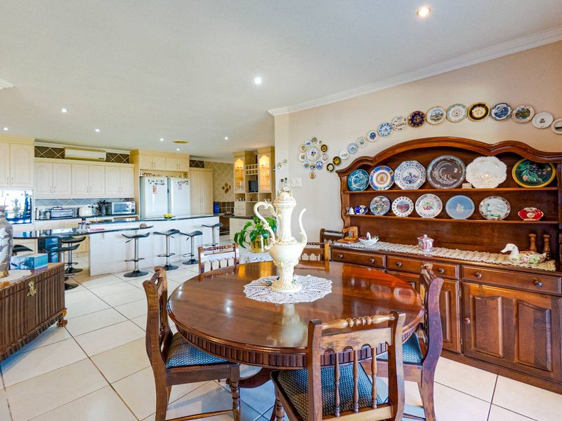 An open-plan kitchen and dining area featuring tiled flooring, recessed lighting, and traditional cabinetry with a breakfast bar.