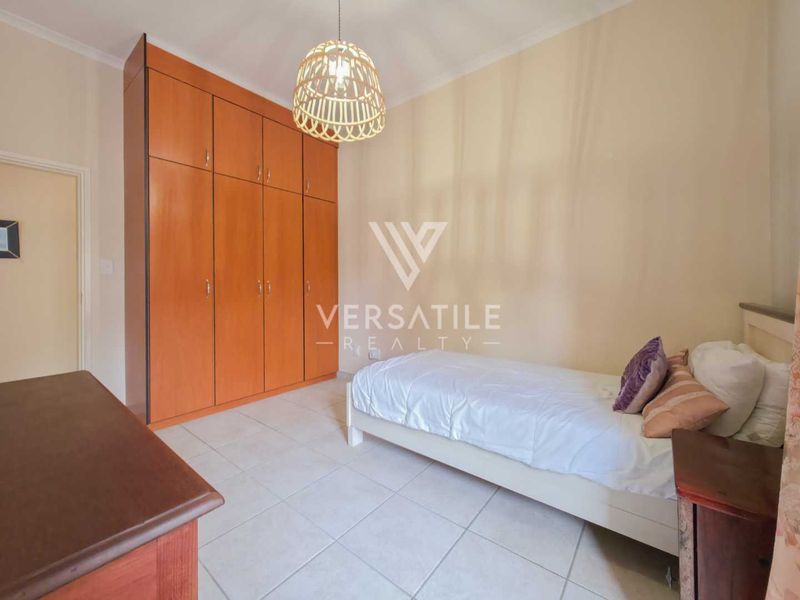 A bedroom featuring tiled flooring and floor-to-ceiling built-in wooden cupboards, providing ample storage space.