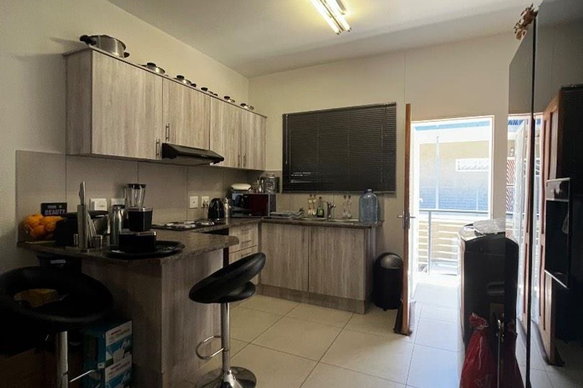 A functional kitchen featuring laminate cabinetry, stone-look countertops, a built-in breakfast bar, and direct access to an outdoor balcony area.
