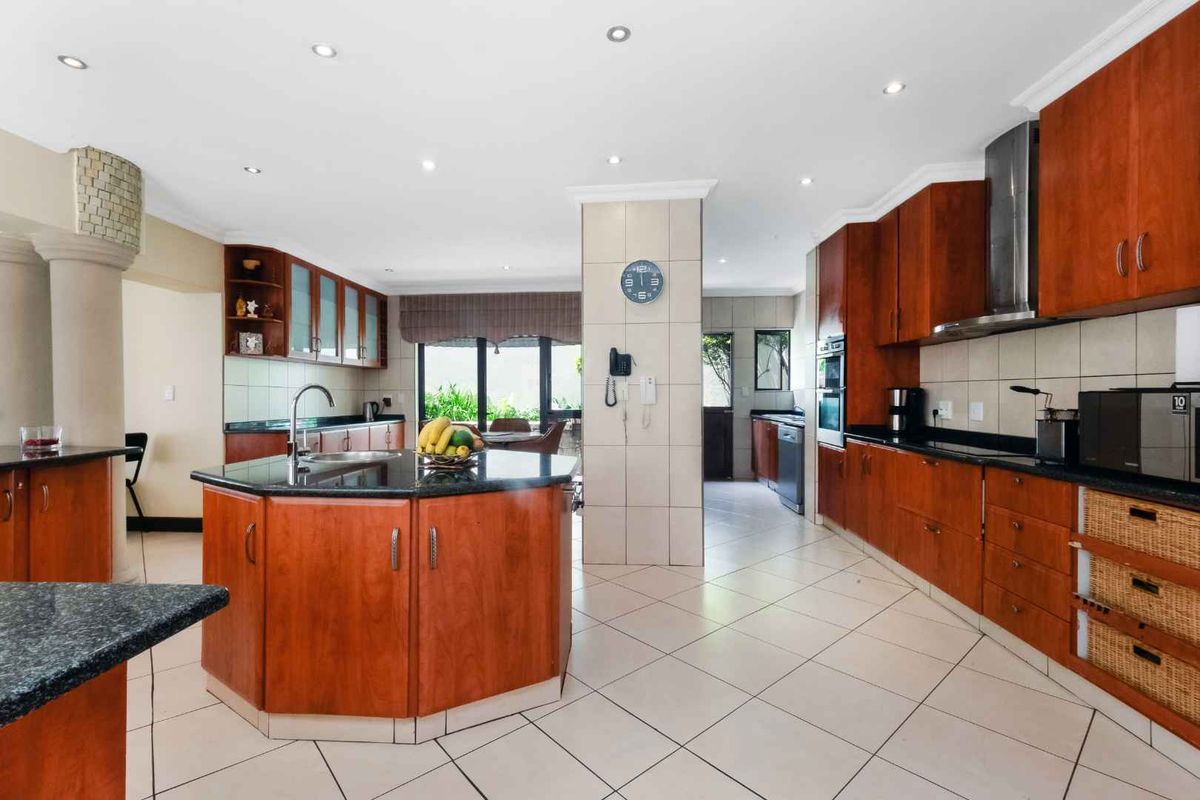 Spacious kitchen featuring dark wood cabinetry, granite countertops, a central island, and integrated stainless steel appliances with recessed ceiling lighting.