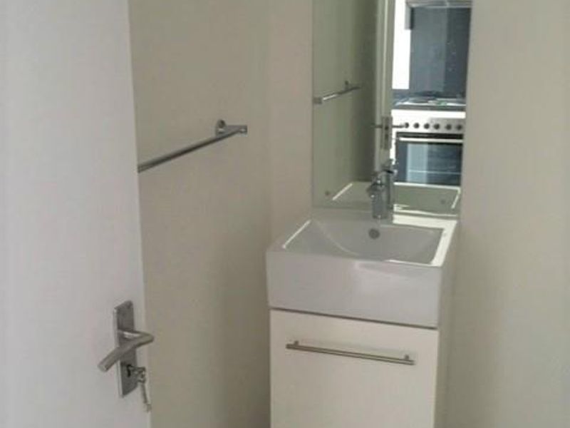 A compact bathroom featuring a modern wall-mounted vanity with a ceramic basin, chrome fixtures, and a large wall-mounted mirror.