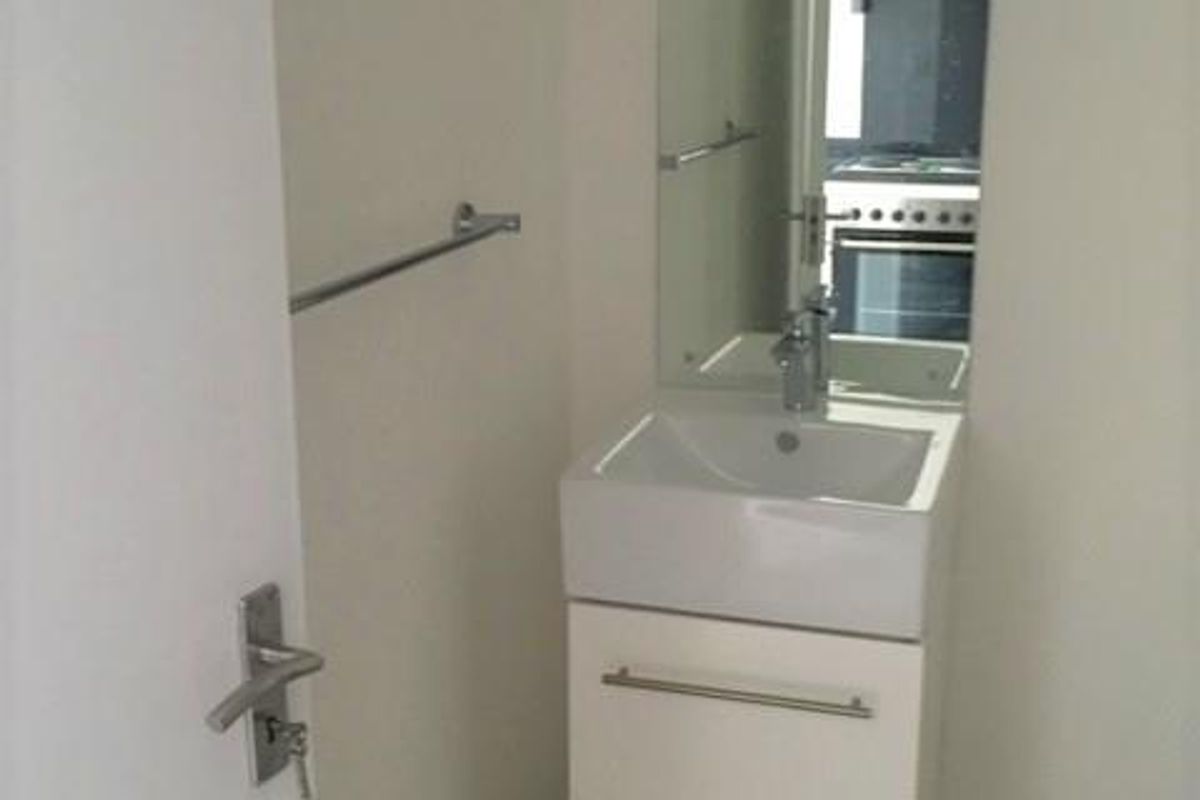 A compact bathroom featuring a modern wall-mounted vanity with a ceramic basin, chrome fixtures, and a large wall-mounted mirror.