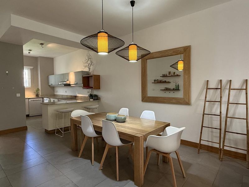 Open plan dining and kitchen area featuring tiled flooring, modern cabinetry, and a breakfast counter, creating a functional and cohesive living space.
