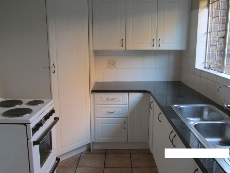 A functional kitchen featuring white cabinetry, dark granite countertops, a double bowl stainless steel sink, and a freestanding electric stove.