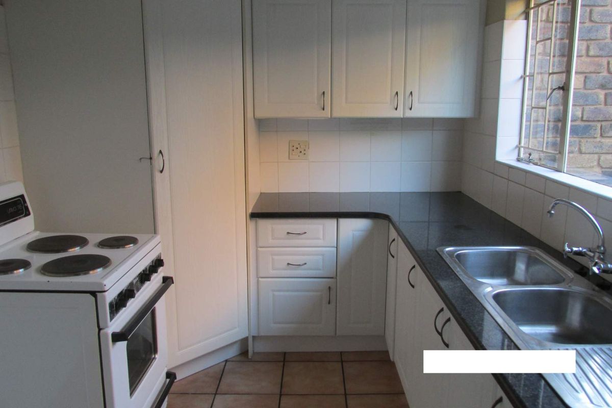 A functional kitchen featuring white cabinetry, dark granite countertops, a double bowl stainless steel sink, and a freestanding electric stove.