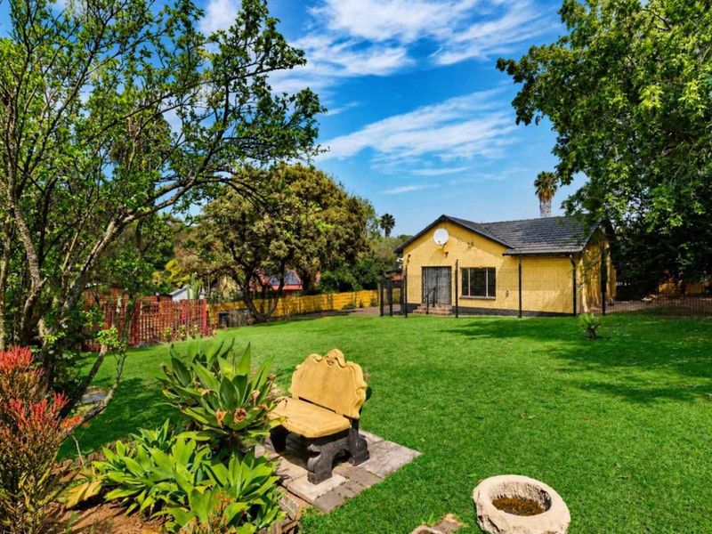A view of the rear exterior of the house featuring a yellow brick facade, tiled roof, and a spacious, well-maintained garden.
