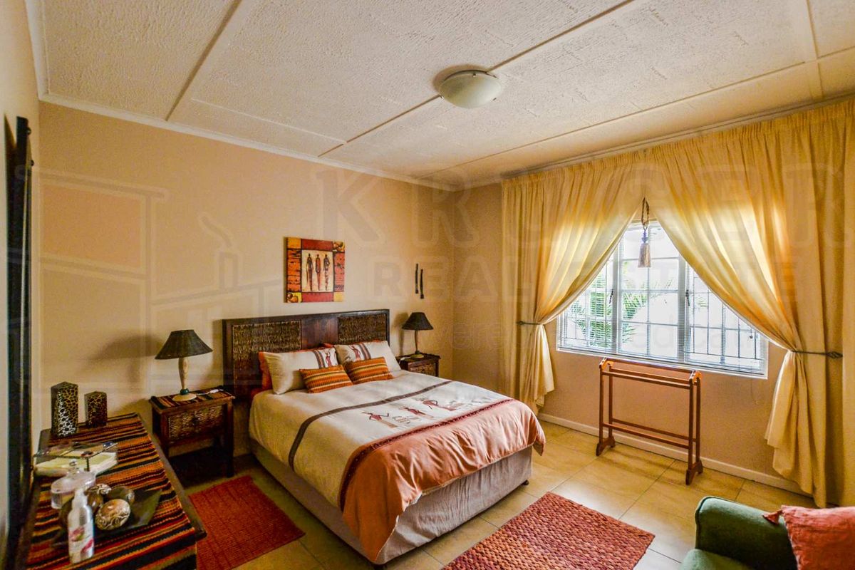 A standard bedroom featuring tiled flooring, a window with security bars, and a central ceiling light fixture.