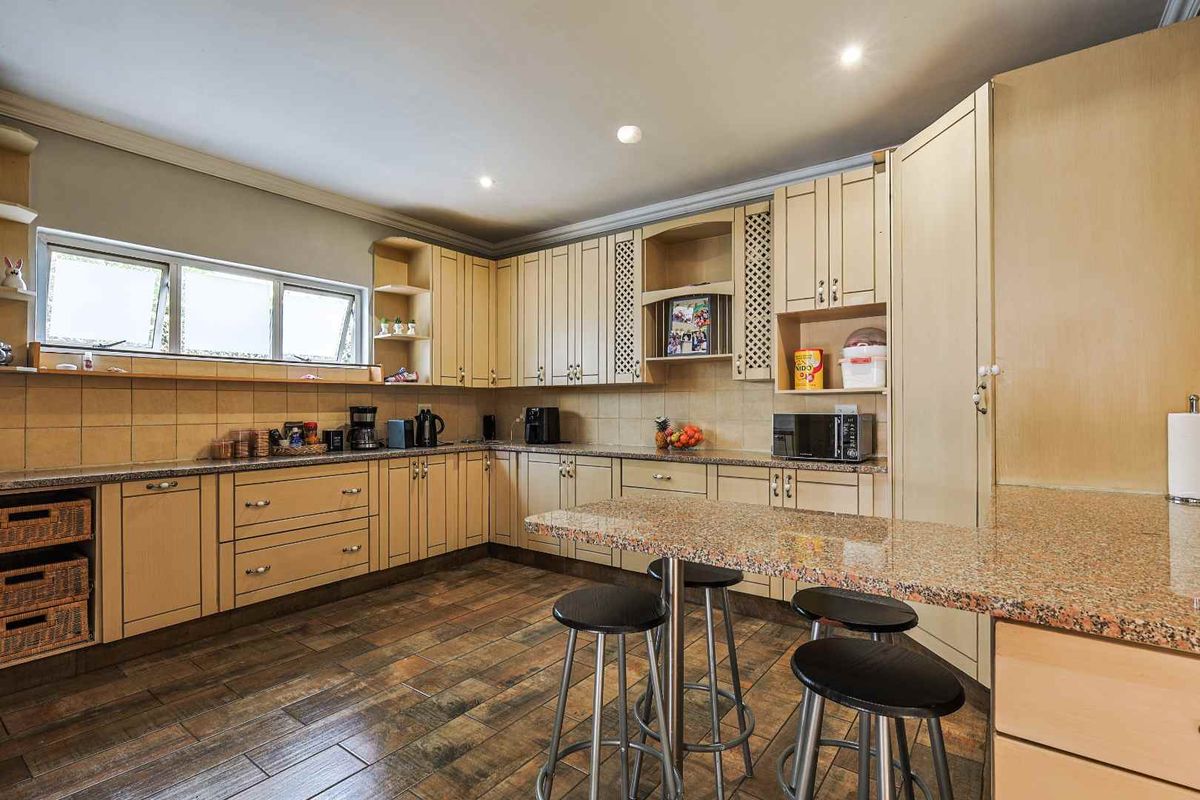 A functional kitchen featuring granite countertops, extensive built-in cabinetry, tiled backsplash, and durable tiled flooring with a breakfast bar area.