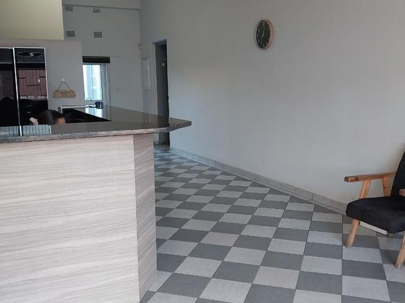 Open plan industrial space featuring a breakfast bar with granite countertop, laminated cabinetry, and distinctive checkered floor tiles.
