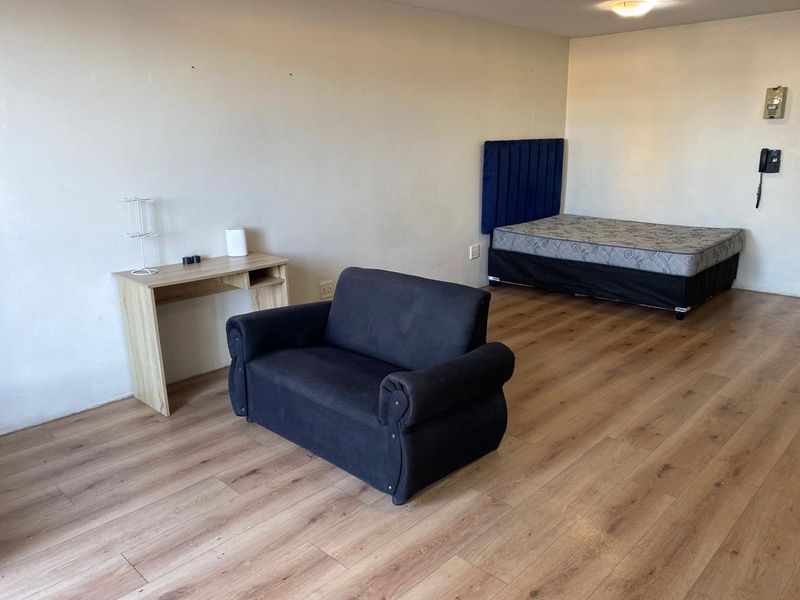 Open plan living and sleeping area featuring laminate flooring and a wall-mounted intercom system.