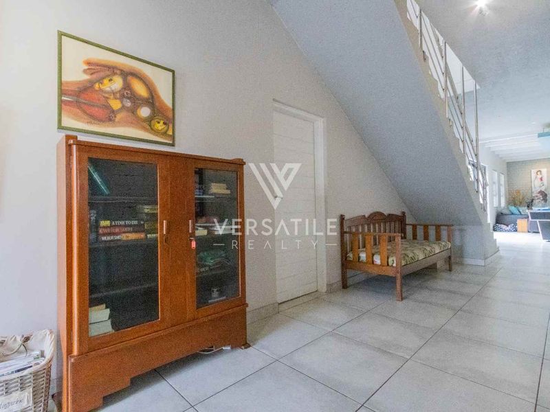 A spacious hallway featuring tiled flooring and a staircase with a metal balustrade, leading towards an open-plan living area.