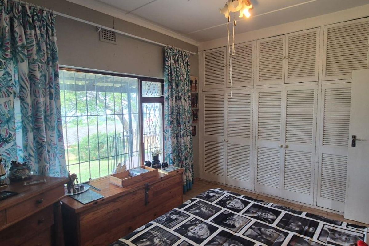 Bedroom featuring extensive built-in louvered cupboards and large windows with security bars, offering a functional layout with potential for modern updates.