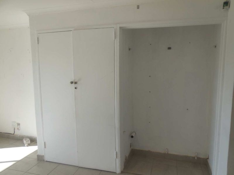 An empty office space featuring tiled flooring and a built-in cupboard, requiring minor cosmetic updates to improve its overall presentation.