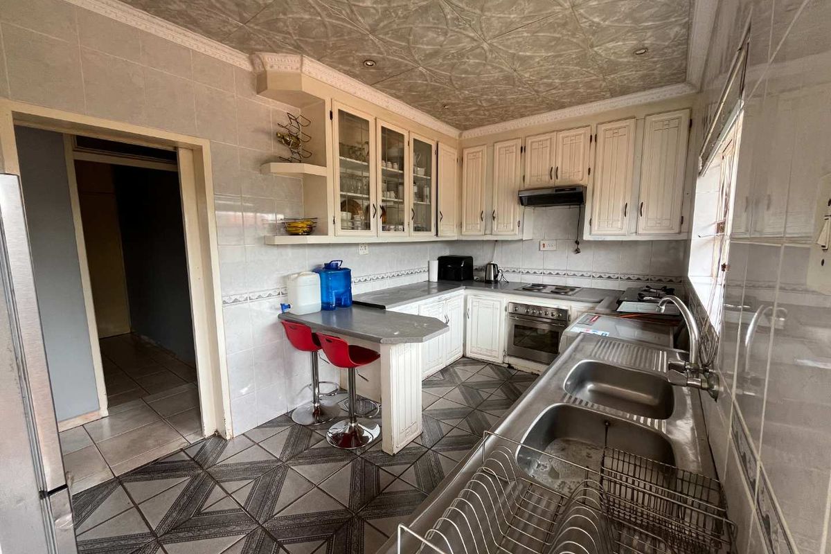 A functional kitchen featuring built-in cabinetry, a double stainless steel sink, integrated oven and hob, and a breakfast bar area.