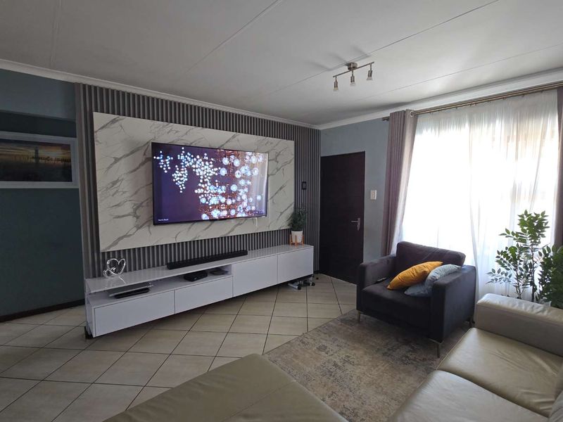 A well-maintained living room featuring a modern marble-look feature wall with integrated slat paneling and tiled flooring.