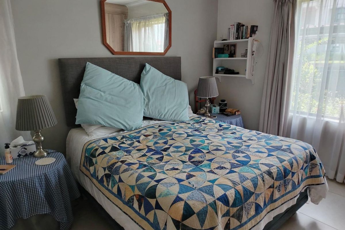 A cozy bedroom featuring neutral wall tones, tiled flooring, and a window with curtains, providing a comfortable and functional sleeping space.