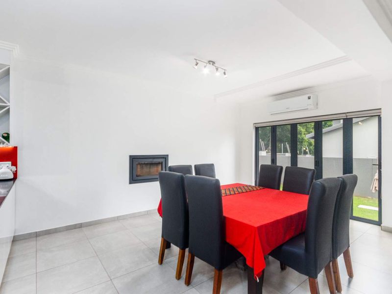 Bright dining area featuring tiled floors, a built-in fireplace, split-system air conditioning, and bi-fold doors providing access to the outdoor space.